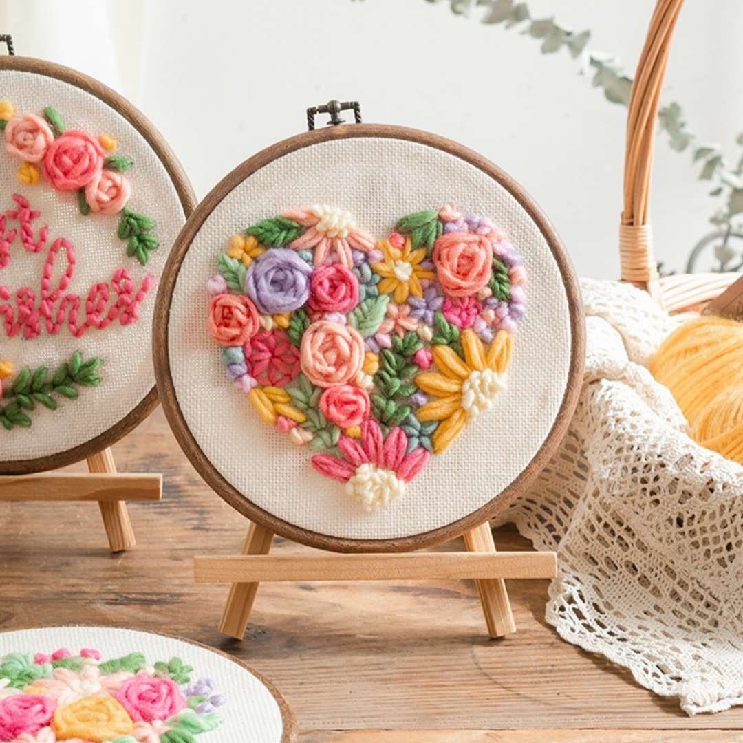 Puddingcase punch needle kit showing a floral heart embroidery design on a wooden stand, perfect for DIY craft enthusiasts.