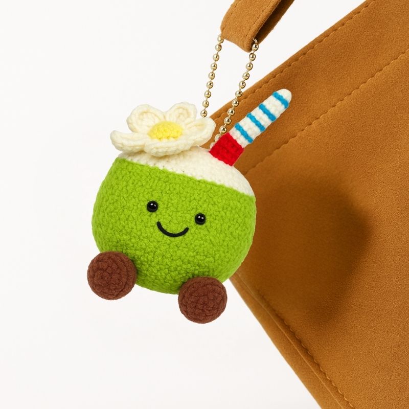 Coconut Cutie amigurumi plush keychain hanging on a brown handbag, made from DIY crochet kit