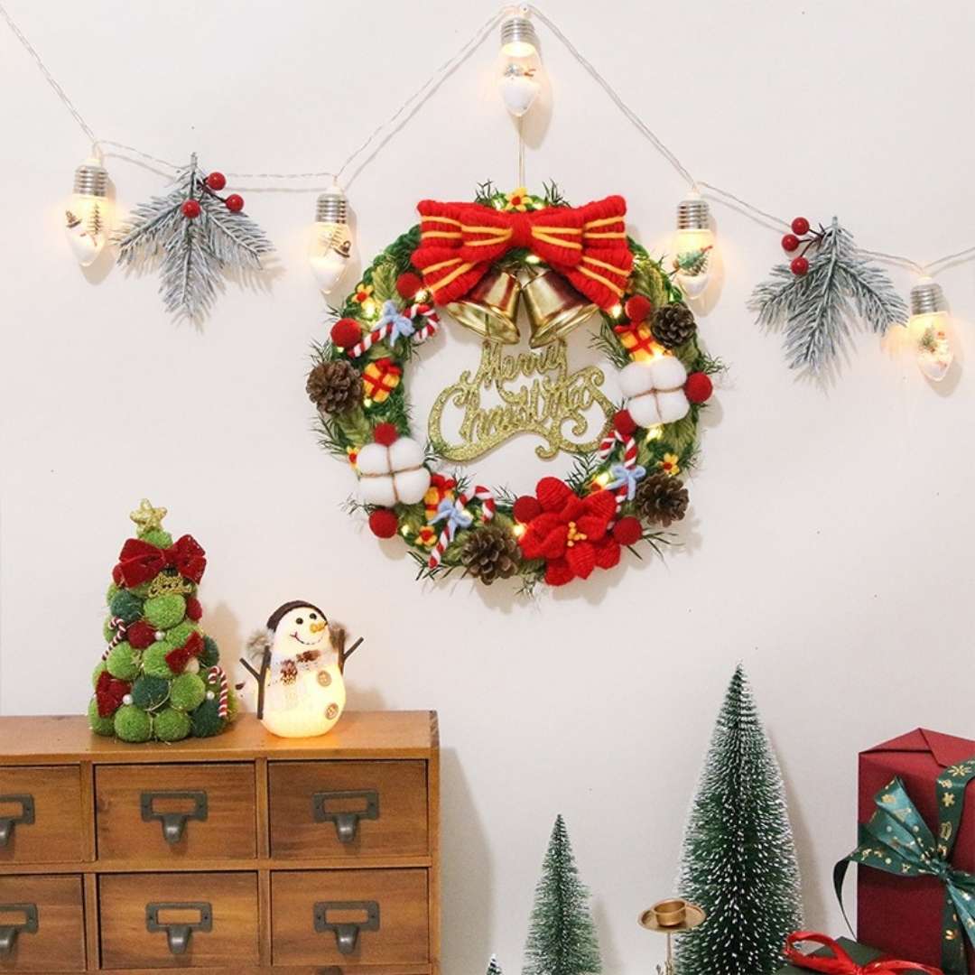 Handmade punch needle Christmas wreath kit with decorative yarn, bells, and festive accessories by Pudding Case.